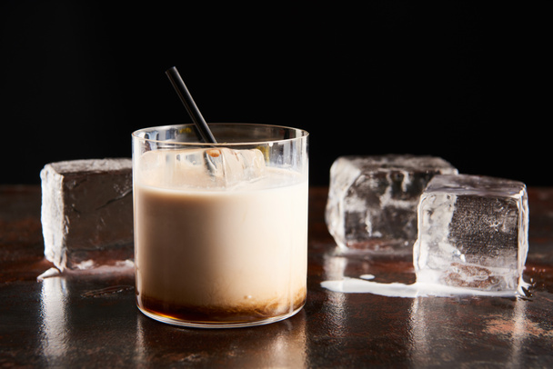white russian cocktail in glass near melting ice cubes isolated on black - Фото, зображення