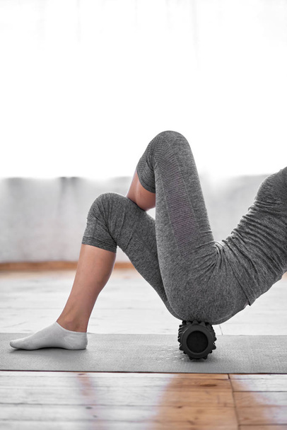 Young woman doing yoga lying on massager on mat on wooden floor in gym - Foto, Imagem