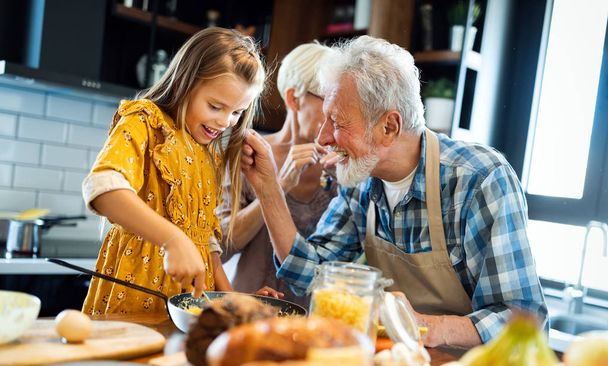Happy elderly couple having breakfast with their grandchildren at home - Фото, изображение