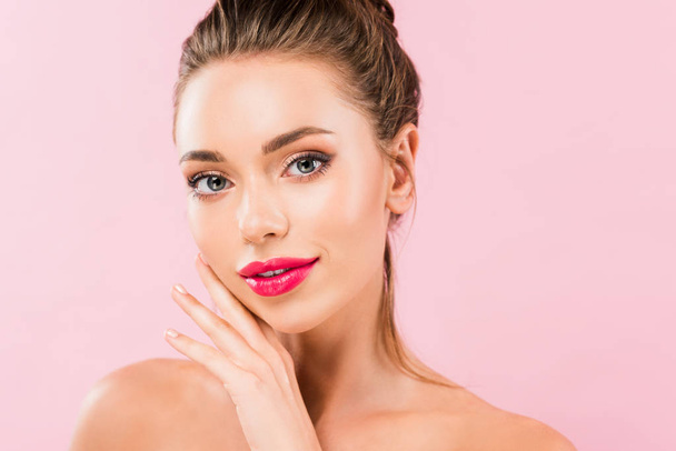 naked beautiful woman with pink lips posing with hand near face isolated on pink  - Foto, Imagen