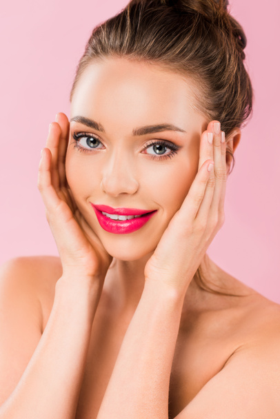 smiling naked beautiful woman with pink lips posing with hands on face isolated on pink  - Photo, Image