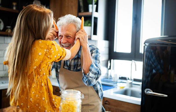 Happy young girl and her grandad cooking together in kitchen - Foto, immagini