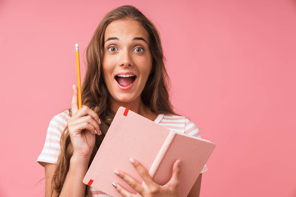 Image closeup of happy young woman wearing striped t-shirt looking at camera while holding diary and pencil - 写真・画像