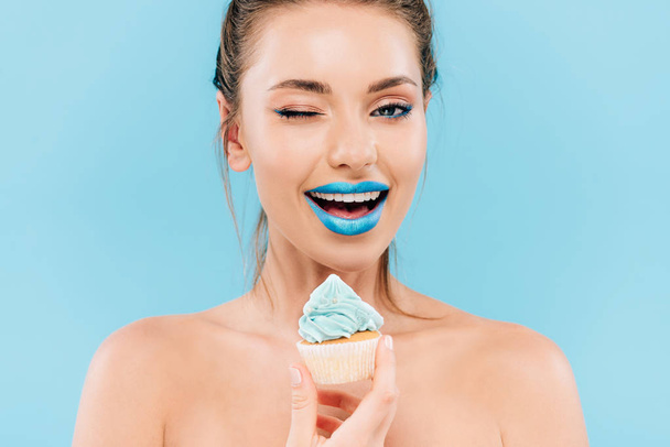 smiling naked beautiful woman with blue lips and cupcake winking isolated on blue - Foto, immagini