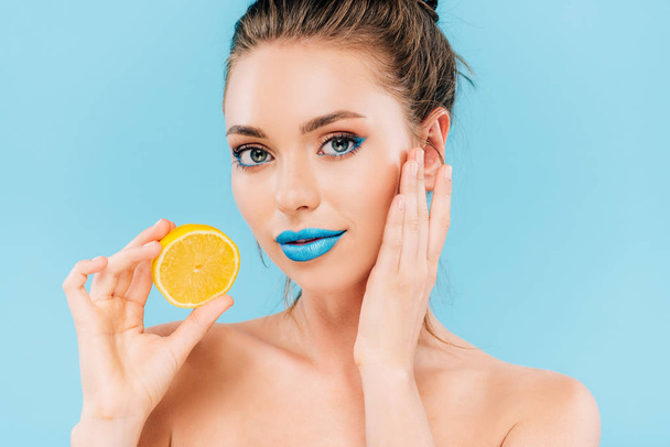 naked beautiful woman with blue lips holding orange half isolated on blue - Foto, afbeelding