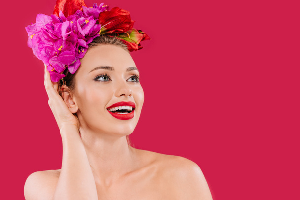 excitada mujer hermosa desnuda con labios rojos y corona floral en la cabeza mirando hacia otro lado aislado en carmesí
 - Foto, imagen