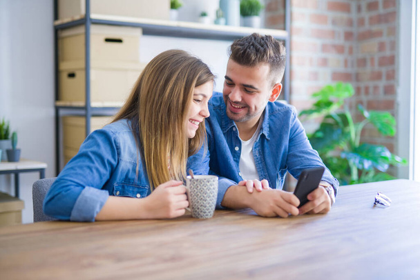Giovane coppia rilassante bevendo una tazza di caffè e utilizzando smartph
 - Foto, immagini