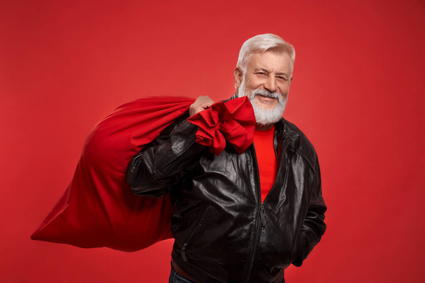 Aged man in red sweater and black jacket with big Santa sack - Photo, Image