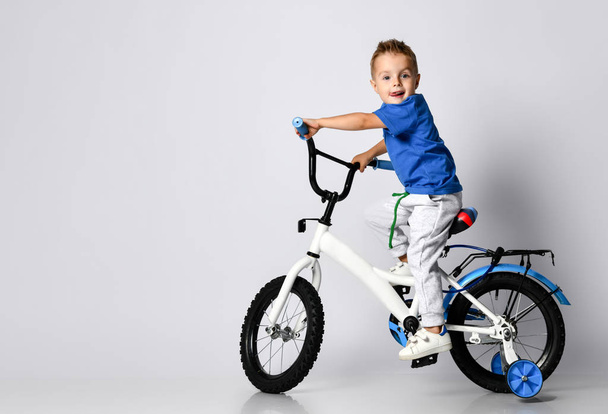 young boy happily riding on a bicycle on isolated background - Valokuva, kuva