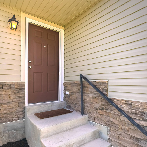 Fachada de casa quadrada com escadas de concreto que levam à porta dianteira de madeira marrom
 - Foto, Imagem