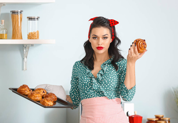 Portrait of beautiful pin-up woman with buns in kitchen - Zdjęcie, obraz