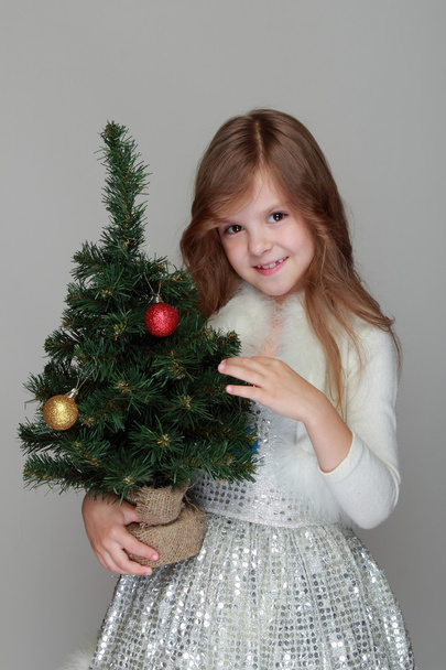 Girl holding a small Christmas tree - Φωτογραφία, εικόνα