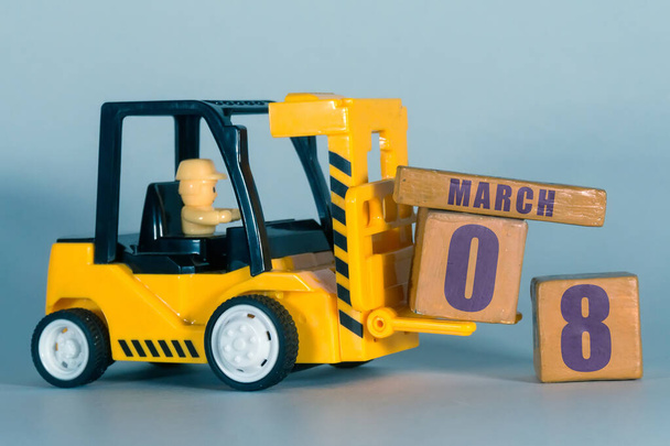 8 marzec. Dzień 8 miesiąca, Budowa lub magazyn kalendarz. Żółty zabawki wózka widłowego załadować drewniane kostki z datą. Planowanie pracy i zarządzanie czasem. miesiąc wiosenny, koncepcja dnia roku - Zdjęcie, obraz