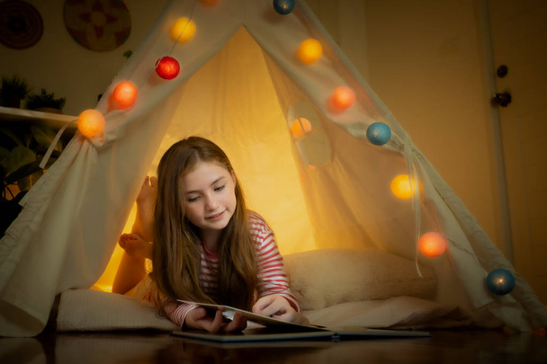 happy little girl reading book and play camping in tents at home - Фото, зображення