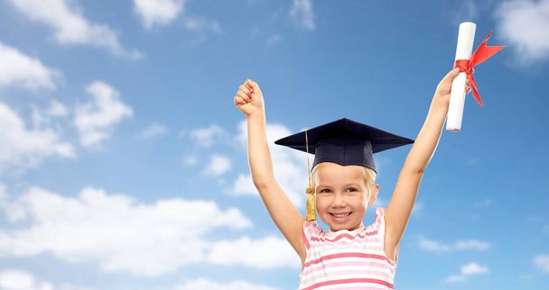 happy little girl in mortarboard with diploma - Foto, Bild