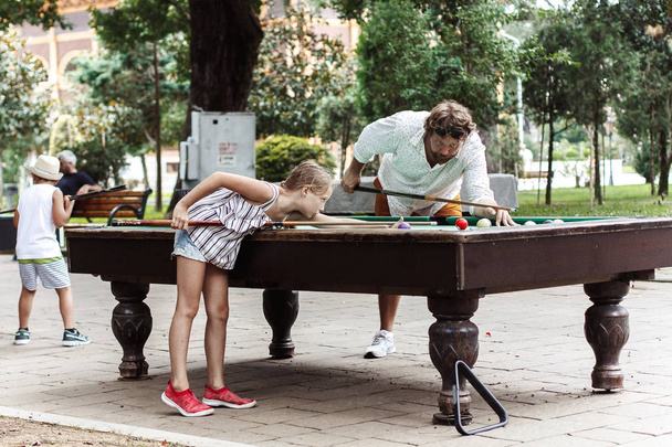 Dad and daughter playing billiards on the street. - Fotoğraf, Görsel