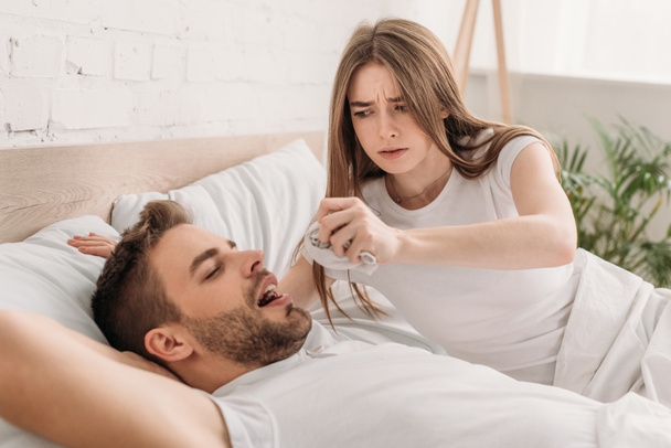dissatisfied woman holding hanky near face of snoring husband - Photo, Image