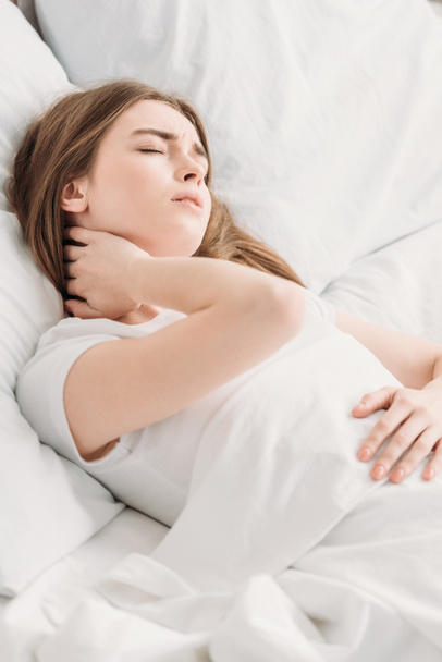 young woman lying in bed with closed eyes while suffering from neck pain - Φωτογραφία, εικόνα