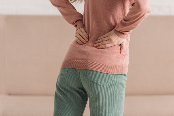 cropped view of woman holding hands on loin while suffering from back pain - Photo, Image