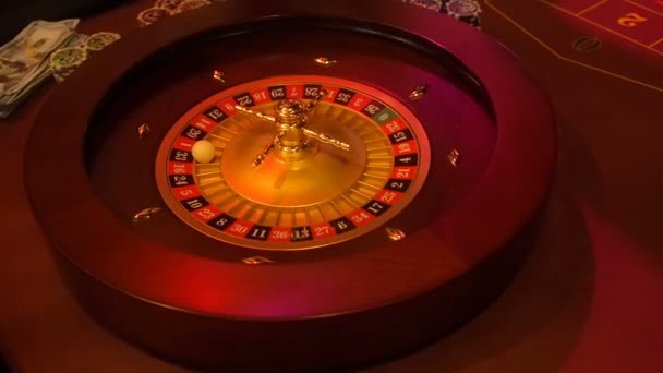 Casino roulette in motion with spinning wheel and ball. Winning number 33 and color red is determined by the roulette wheel. Roulette table layout in low light. Roulette with red 33 as the winner - Footage, Video