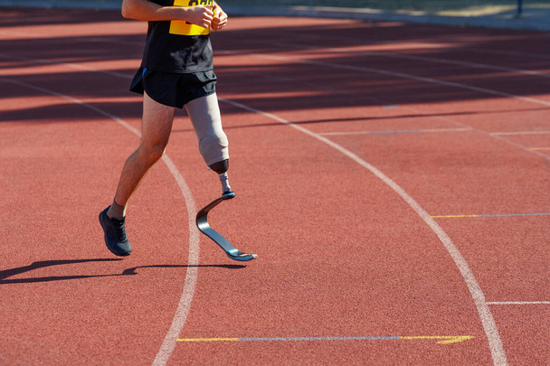 Man with prosthetic leg running at a stadium - Photo, Image