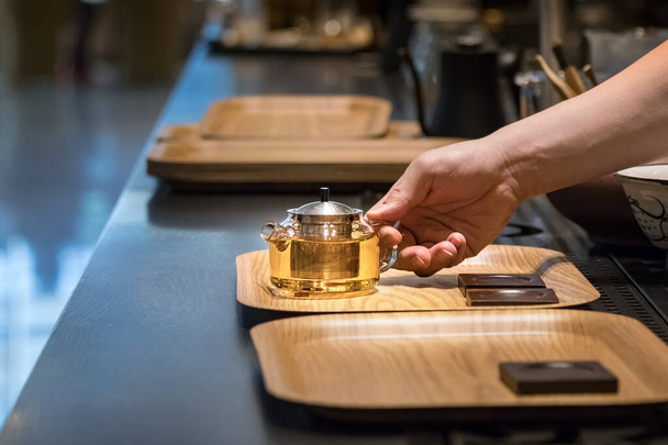 Чоловічі руки бариста кладуть скляний чайник з чаєм у нитки на піднос у кафе в Пусані (Південна Корея). - Фото, зображення