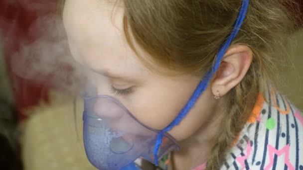 Kind mit Tablette ist krank und atmet durch einen Inhalator. Nahaufnahme. Das kleine Mädchen wurde mit einer Inhalationsmaske im Gesicht im Krankenhaus behandelt. Kleinkind behandelt Grippe durch Einatmen von Inhalationsdampf. - Filmmaterial, Video