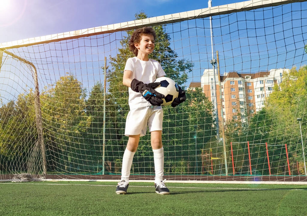 Summer soccer tournament for young kids. football club. emotions and joy of the game. Young goalie. Kids - soccer champion. Boy goalkeeper in football sportswear on stadium with ball. Sport concept. - Foto, immagini