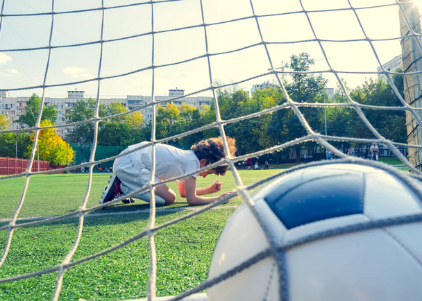 Young boy or kid plays soccer or football sports for exercise and activity. View from behind the goal nets. selective focus - Photo, Image