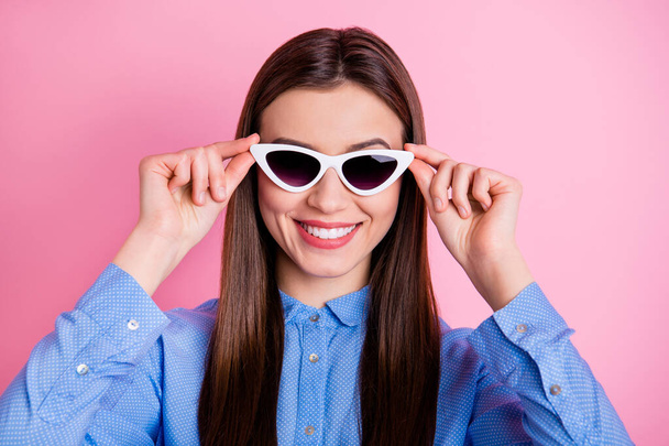 Close up photo of cute nice fascinating good lady wearing sunglass eyewear holding them with hands smiling toothily isolated over pink pastel color background - Photo, image