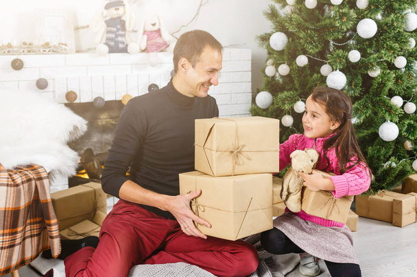 glücklicher junger Vater und seine Tochter zu Hause mit Weihnachtsbaum  - Foto, Bild