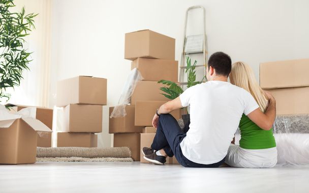Couple sitting in room full of moving boxes - Foto, Imagen