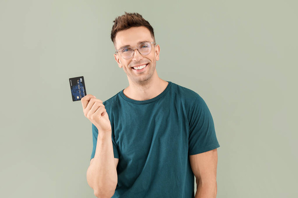Young man with credit card on color background - 写真・画像
