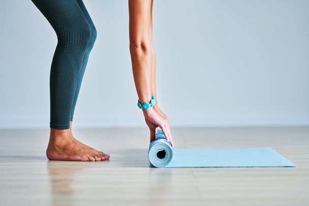 Young woman rolling yoga mat at home - Photo, image