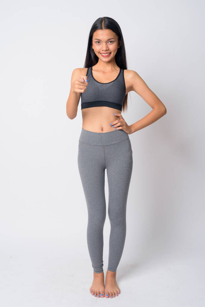 Full body shot of happy young Asian woman pointing at camera ready for gym - Foto, Imagen