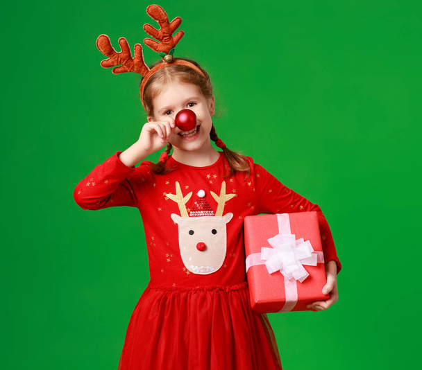 happy funny child girl in red Christmas reindeer costume with gi - Foto, Bild