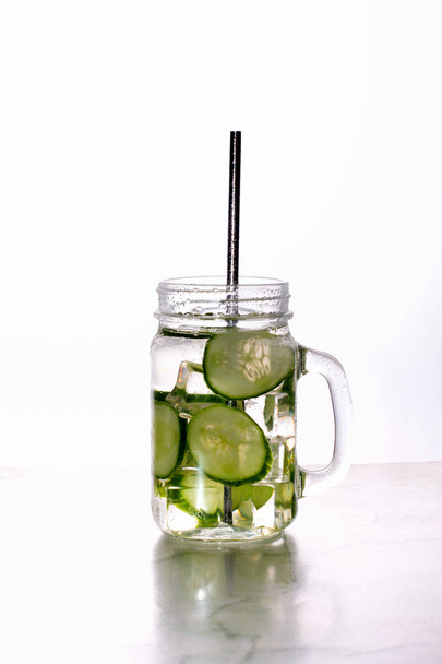 Glass of cucumber water with ice on white background. - Foto, imagen
