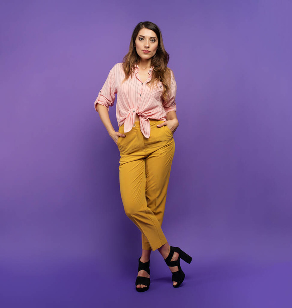 Брюнетка в жёлтой и розовой одежде на фиолетовом фоне. концепция моды и покупок
 - Фото, изображение