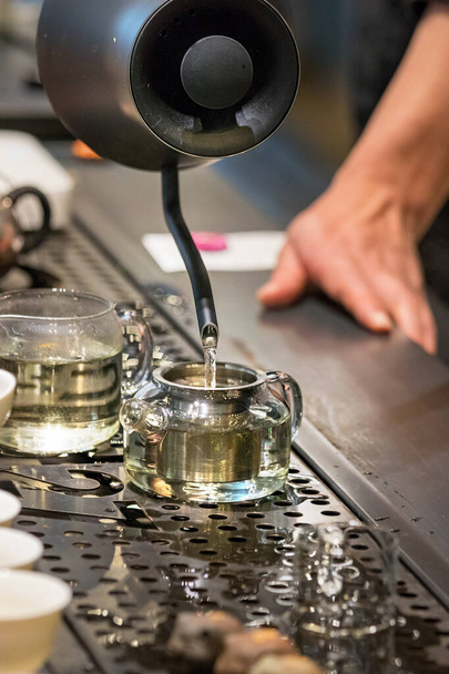 Чоловічі руки виливають гарячу воду на скляні чайники, які роблять чай у нитках біля прилавка в Пусані (Південна Корея). - Фото, зображення