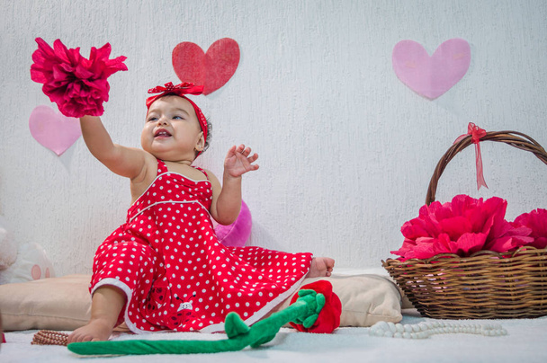 Kırmızı elbiseli küçük kız kağıt çiçekler ve kalpler - Fotoğraf, Görsel