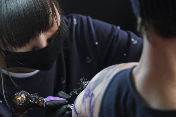 Brüksel, Belçika. 9 Kasım 2019. Uluslararası Brüksel Dövme Kongresi sırasında bir dövme sanatçısı bir kişiye dövme yaptırdı. - Fotoğraf, Görsel