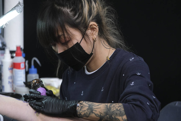Brussels, Belgium. Nov. 9th, 2019. A Tattoo artist  tattooed a person during the International Brussels Tattoo Convention. - Foto, imagen