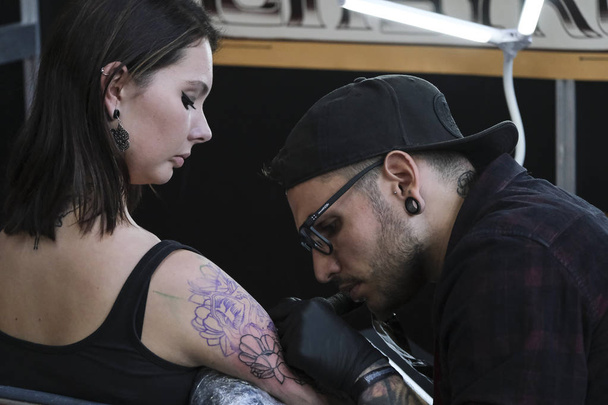 Bruxelles, Belgique. 9 nov. 2019. Un tatoueur a tatoué une personne lors de la Convention internationale de Bruxelles sur le tatouage
. - Photo, image
