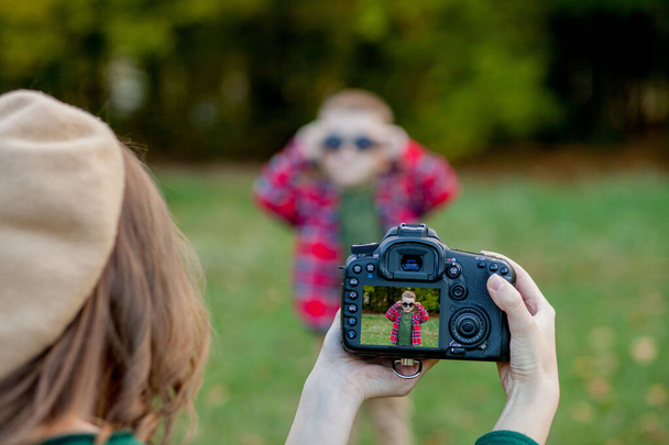 Fotoğrafçı kadın, dışarıda parkta geçirmek için çocuğun fotoğrafını çekiyor. - Fotoğraf, Görsel