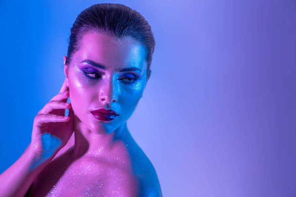 Gorgeous brunette model in the studio with color filters. Fashion, beauty, glow. Closeup face of a beautiful brunete woman in neon light purple and blue. - Foto, Imagem