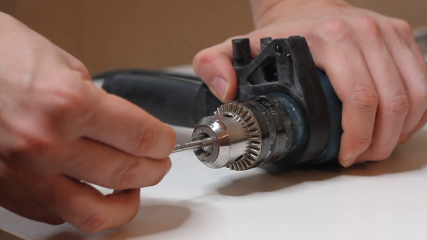 Detailní záběr mladého muže připravuje elektrický vrták a mění vrták na vrták - Záběry, video