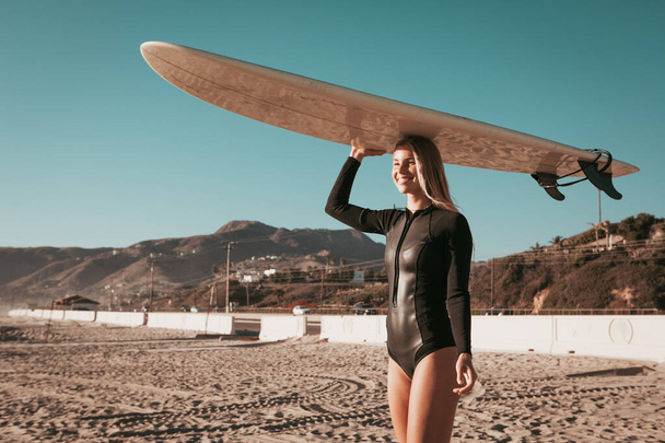 jonge vrouw met surfplank op het strand van Malibu. california levensstijl - Foto, afbeelding