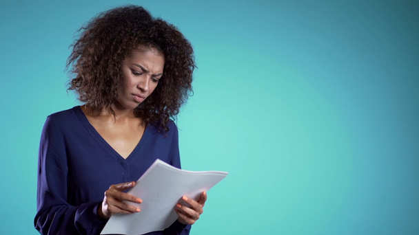 Copy space. Serious african businesswoman boss on blue background. She is unsatisfied with work of staff. Young female office employee checks documents, reports. - Metraje, vídeo