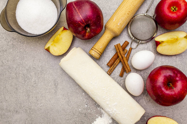 Jabłecznik składniki pieczenia koncepcja. Świeże jabłka z cynamonem, mąką, cukrem, jajkami. Proces gotowania na kamiennym tle, widok z góry - Zdjęcie, obraz