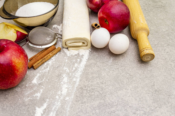 Ingredientes de torta de maçã conceito de cozimento. Maçãs frescas com canela, farinha, açúcar, ovos. Processo de cozimento no fundo de pedra, vista superior
 - Foto, Imagem